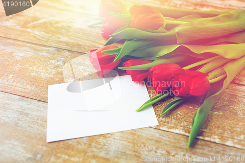 Image of close up of red tulips and blank paper or letter