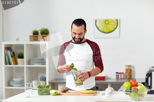 Image of man with blender cup cooking food at home kitchen