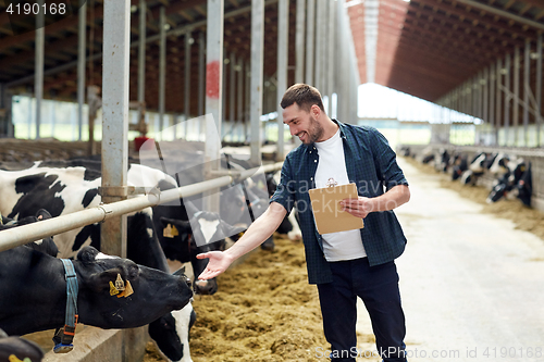 Image of farmer with clipboard and cows in cowshed on farm