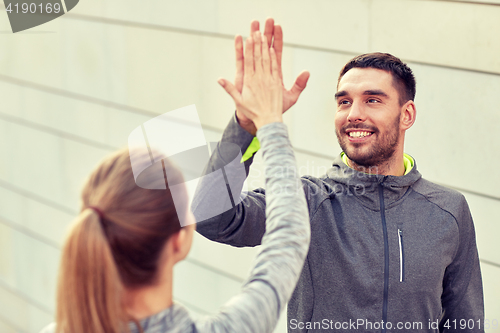 Image of happy couple giving high five outdoors