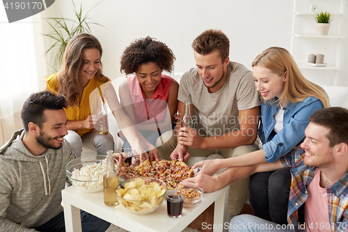 Image of happy friends with drinks eating pizza at home