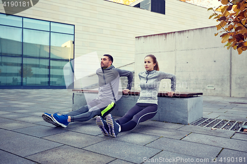 Image of couple doing triceps dip exercise outdoors