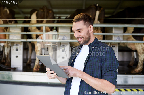 Image of young man with tablet pc and cows on dairy farm