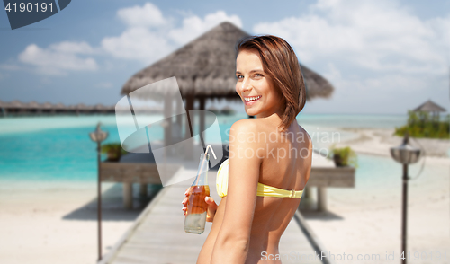 Image of happy woman with bottle of drink on summer beach