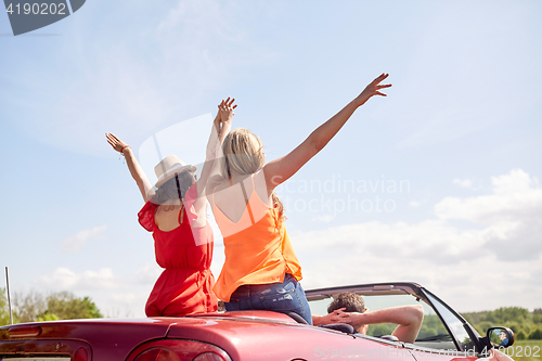 Image of happy friends driving in cabriolet car at country