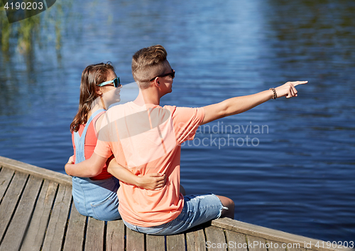 Image of happy couple pointing finger on summer river berth