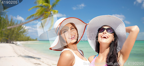 Image of happy young women in hats on summer beach