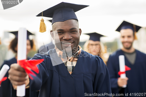 Image of happy students in mortar boards with diplomas