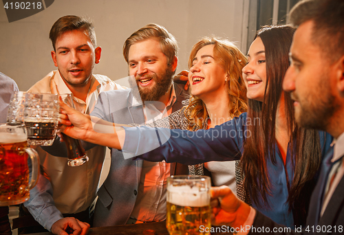 Image of Group of friends enjoying evening drinks with beer