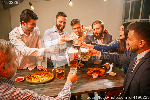 Image of Group of friends enjoying evening drinks with beer