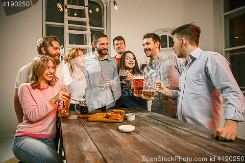 Image of Group of friends enjoying evening drinks with beer