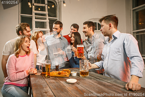 Image of Group of friends enjoying evening drinks with beer