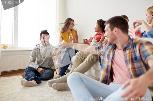 Image of group of happy friends with drinks talking at home