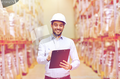 Image of happy businessman with clipboard at warehouse