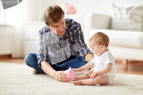 Image of happy father with baby and piggy bank at home