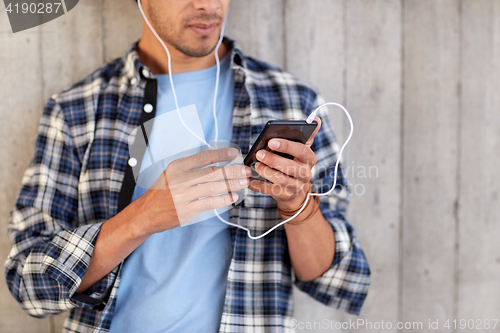 Image of man with earphones and smartphone listening music