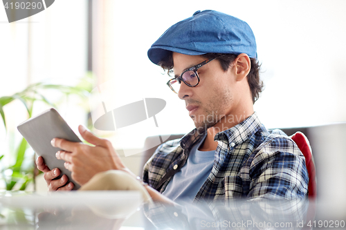 Image of man with tablet pc sitting at cafe table