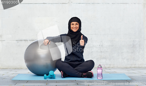 Image of muslim woman in hijab with fitness ball and bottle