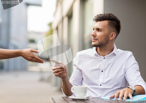 Image of man with credit card paying for coffee at cafe