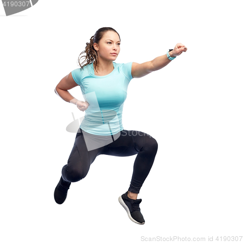 Image of happy sporty young woman jumping in fighting pose