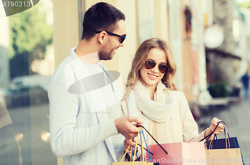 Image of happy couple with shopping bags on city street