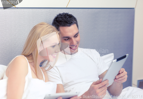 Image of smiling couple in bed with tablet pc computers