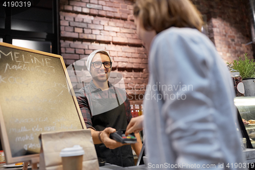 Image of happy woman paying for purchases at cafe