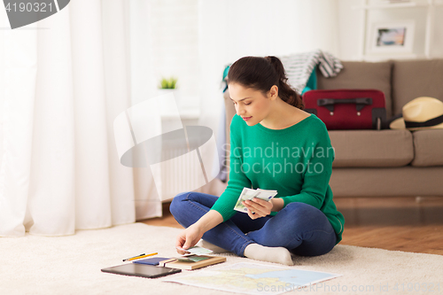 Image of happy woman with money and travel map at home