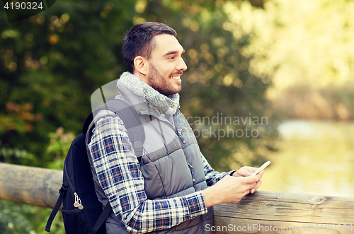 Image of happy man with backpack and smartphone outdoors