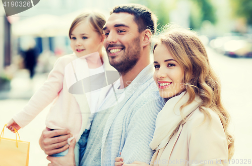 Image of happy family with child and shopping bags in city
