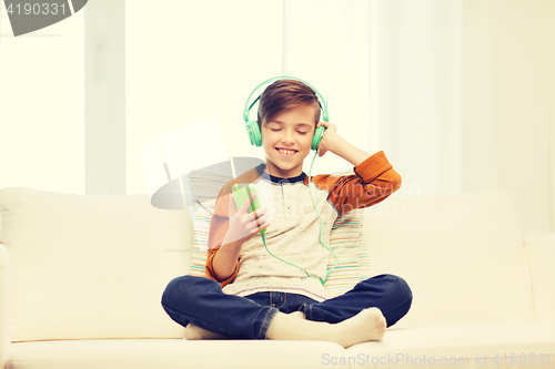 Image of happy boy with smartphone and headphones at home