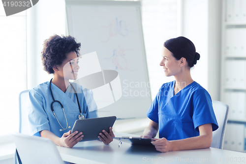 Image of happy doctors with tablet pc meeting at hospital