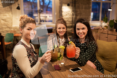 Image of happy friends clinking drinks at restaurant