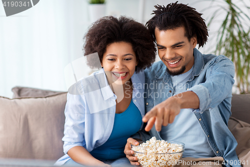 Image of smiling couple with popcorn watching tv at home