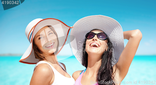 Image of happy young women in hats on summer beach