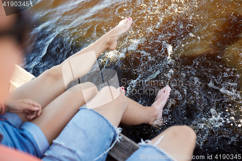 Image of legs of young couple sitting on river berth