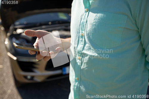 Image of close up of man with smartphone and broken car