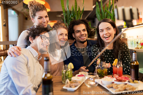 Image of friends taking selfie by smartphone at bar or cafe