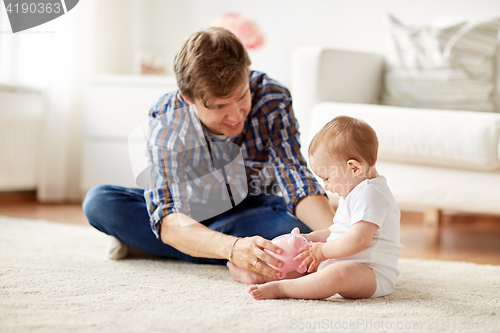 Image of happy father with baby and piggy bank at home