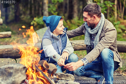 Image of father and son roasting marshmallow over campfire