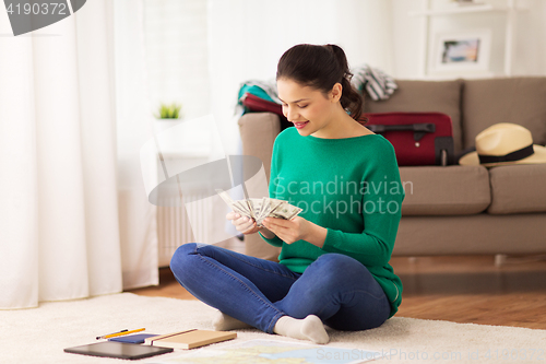 Image of happy woman with money and travel map at home