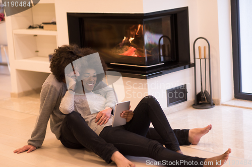 Image of multiethnic couple used tablet computer on the floor