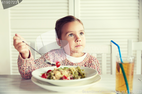 Image of little girl eating pasta for dinner at restaurant