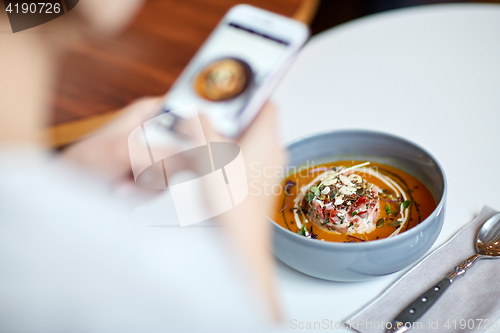 Image of woman with smartphone photographing food at cafe