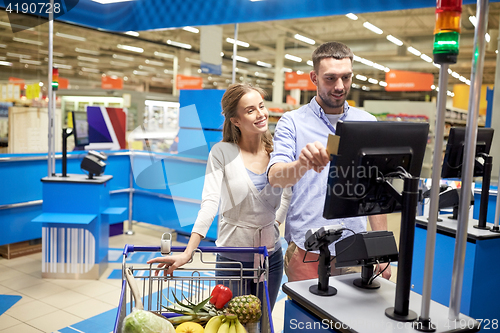 Image of couple buying food at grocery store cash register