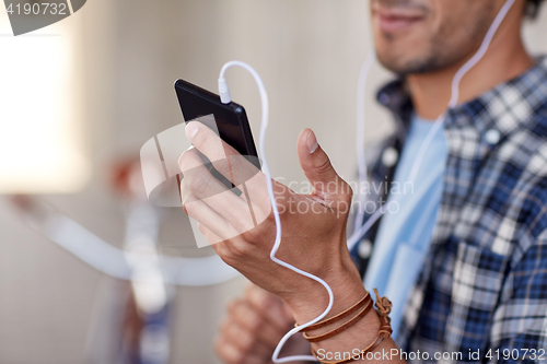 Image of man with earphones and smartphone listening music