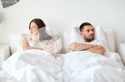 Image of unhappy couple having conflict in bed at home