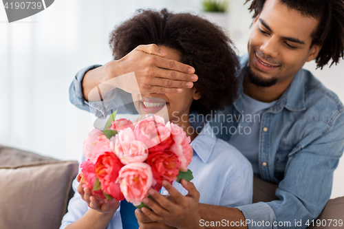 Image of happy couple with bunch of flowers at home
