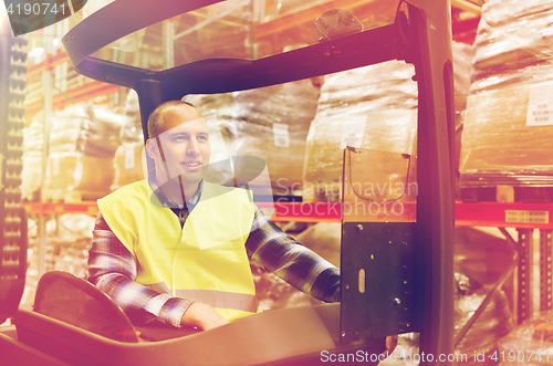 Image of smiling man operating forklift loader at warehouse