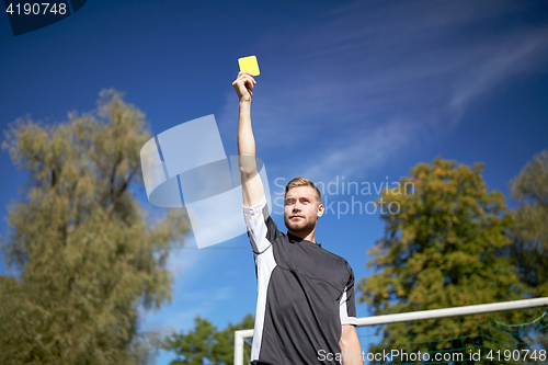 Image of referee on football field showing yellow card